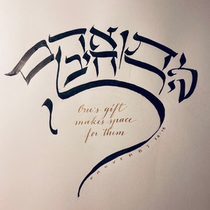 May include: Black ink calligraphy on white paper with the Hebrew words "One's gift makes space for them" and the text "Proverbs 18:16" in gold ink.