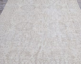 May include: A large, rectangular rug with an intricate floral pattern in shades of cream and beige. The rug has a detailed border and a distressed, vintage appearance, suitable for living rooms or bedrooms.