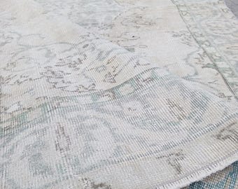 Puede incluir: Una alfombra vintage blanca y azul claro con un aspecto desgastado y un borde con flecos.