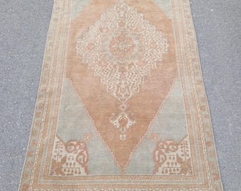 Puede incluir: Una alfombra vintage con una combinación de colores marrón claro y beige. La alfombra tiene un medallón central en forma de diamante con intrincados patrones florales. La alfombra tiene un borde con un patrón repetitivo de pequeños motivos florales.