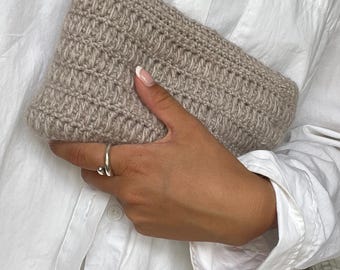 May include: A beige crocheted zippered pouch held in a hand. The pouch has a textured, woven pattern.