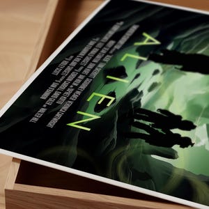 Puede incluir: Un p&oacute;ster negro y verde con la palabra "ALIEN" en letras blancas grandes. El p&oacute;ster presenta una escena oscura y atmosf&eacute;rica con siluetas de personas caminando por un paisaje verde y negro.