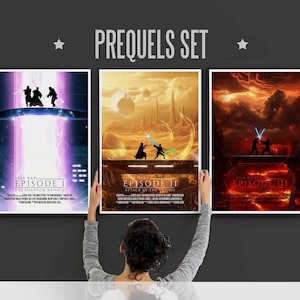 May include: Three Star Wars movie posters featuring the prequel trilogy. The posters are in a dark room with a person holding them up. The posters are for Episode I: The Phantom Menace, Episode II: Attack of the Clones, and Episode III: Revenge of the Sith.