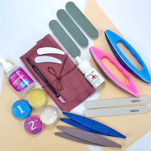 Puede incluir: Un kit de cuidado de uñas con varias herramientas y productos. Incluye limas de uñas, pulidores, removedor de cutículas y polvos. El kit presenta botellas y recipientes con el texto "MAGIC GIRL". La paleta de colores incluye rosa, azul, gris y blanco.