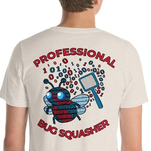 Puede incluir: Una camiseta beige claro con un gráfico rojo y azul de un insecto con un matamoscas. El gráfico dice "Professional Bug Squasher" y está rodeado de código binario.
