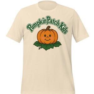 May include: Cream-colored t-shirt featuring a smiling orange pumpkin on green leaves, with the text "Pumpkin Patch Kids" in green script. The shirt has short sleeves and a crew neck.