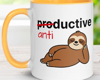 May include: White ceramic mug with a yellow handle and interior. The mug features the text "anti" in red below the word "productive" with a red line through it. A cartoon sloth is drawn on the mug.