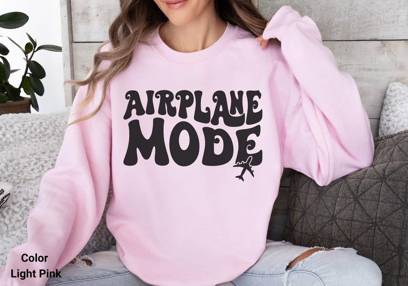 May include: A light pink sweatshirt with the text "AIRPLANE MODE" in black retro font. A small airplane icon is below the text.