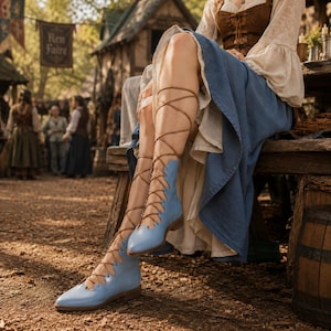 May include: Light blue calf-high boots featuring a pointed toe and a lace-up front design with thin brown laces that wrap around the lower leg. The boots have a flat sole and a smooth finish, worn with a long blue skirt and a brown corset top.