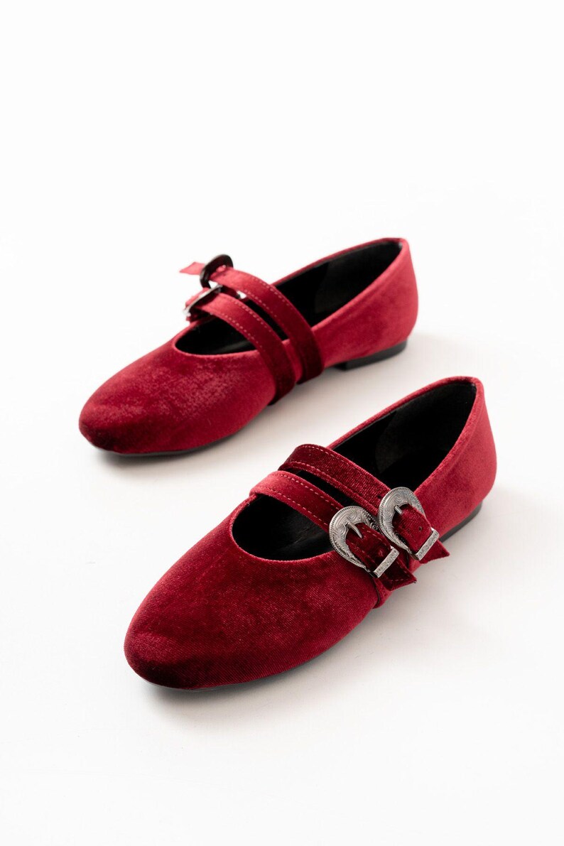 May include: A pair of red velvet flats with double silver buckles. The shoes have a pointed toe and a low heel.