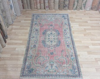 May include: A vintage pink and cream rug with a floral pattern. The rug has a faded look and is in good condition.