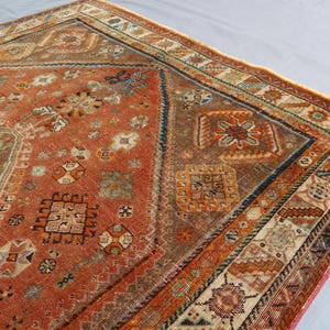 May include: A vintage rug with a red, orange, and blue geometric pattern. The rug has a faded, worn look and is made of wool.