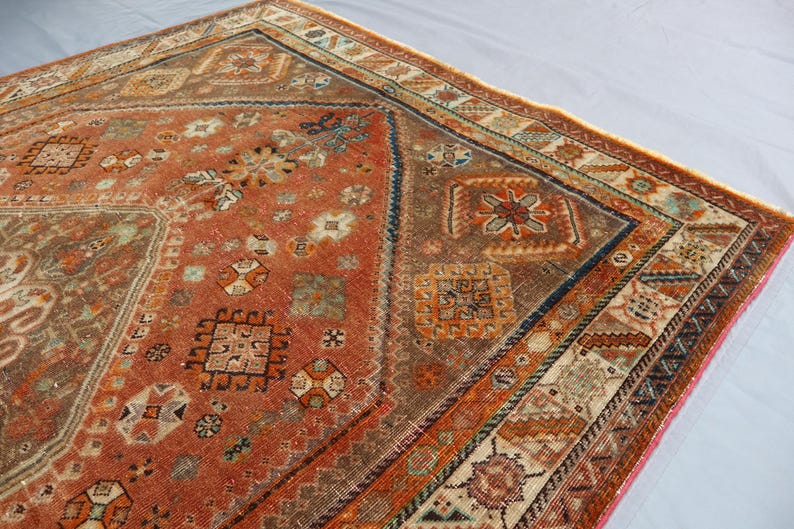 May include: A vintage rug with a red, orange, and blue geometric pattern. The rug has a faded, worn look and is made of wool.