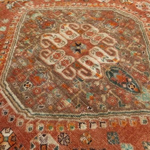 May include: A vintage rug with a central medallion design in shades of brown, red, and white. The rug has a geometric pattern with intricate details.