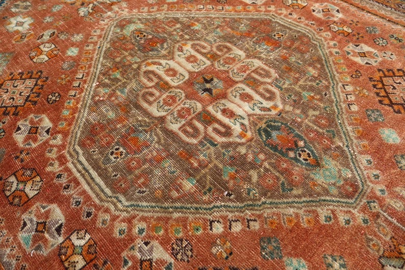 May include: A vintage rug with a central medallion design in shades of brown, red, and white. The rug has a geometric pattern with intricate details.