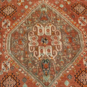 May include: A vintage rug with a geometric pattern in shades of red, brown, and beige. The rug has a central medallion with a floral design and a border with repeating motifs.