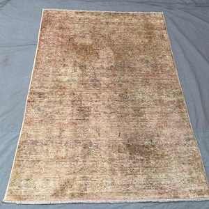 May include: A rectangular, distressed rug with a faded, vintage appearance. The rug features a blend of beige, brown, and muted green tones, creating a textured, aged look. The edges have a subtle fringe detail, adding to its classic appeal.