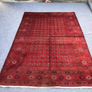 May include: A red rug with a traditional Persian design. The rug has a dark red background with intricate patterns in shades of brown, beige, and cream.