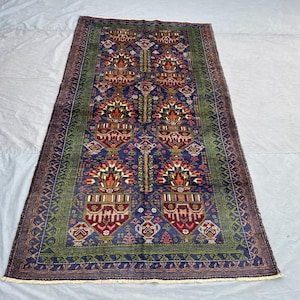 May include: Rectangular, hand-knotted rug with a central navy blue field featuring repeating floral motifs in red, orange, and white. The rug has a green border and a dark brown outer edge. The rug's dimensions are approximately 3 x 5 feet.