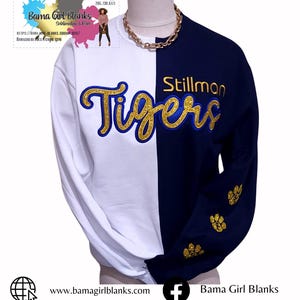 May include: A white and navy blue sweatshirt with the words "Stillman Tigers" in gold glitter lettering on the front. The sweatshirt has paw prints on the sleeves.