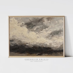 Könnte beinhalten: Gerahmtes Landschaftsgemälde mit goldfarbenem Rahmen. Das Kunstwerk zeigt einen dramatischen Himmel mit dunkelgrauen und weißen Wolken. Der untere Teil des Gemäldes hat eine dunkelbraune Farbe. Der Text "EMPORIUM PRINTS art collective" ist unten aufgedruckt.