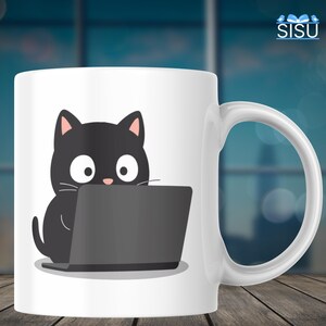 Pode incluir: Caneca de cerâmica branca com um gato preto de desenho animado em frente a um laptop cinza. O gato tem olhos grandes e orelhas rosadas. A caneca tem uma alça grande. O fundo está desfocado.
