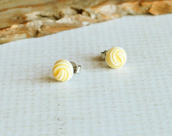 May include: A pair of yellow and white swirl stud earrings. The earrings are small and round, and they have a simple design.