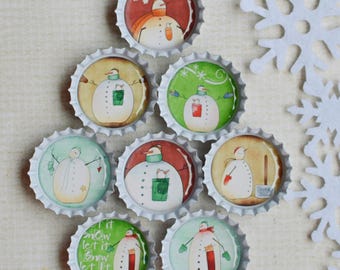 May include: Eight silver-colored metal bottle caps arranged in a triangular shape, each featuring a unique illustration of a snowman. Beside the caps are five white, die-cut paper snowflakes. One cap includes the text Let it snow.