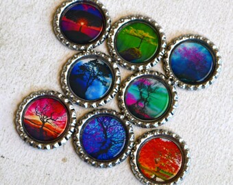 May include: Eight round bottle caps with colorful images of trees and landscapes. The bottle caps are silver with a raised edge.