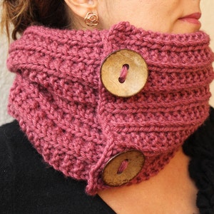 May include: A pink knitted neck warmer with two large wooden buttons.