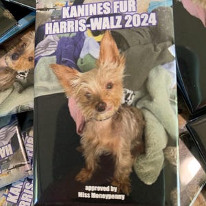 Peut inclure: Un bouton noir et blanc avec une image d'un petit chien brun et blanc. Le texte sur le bouton indique "Kanines for Harris-Walz 2024" et "approved by Miss Moneypenny".