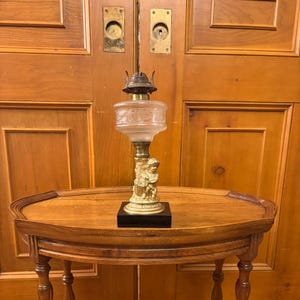 Antique late 19th century petite gilded figural oil lamp with patterned glass.