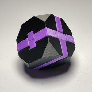 Può includere: Un puzzle geometrico nero e viola con più lati e un design complesso.