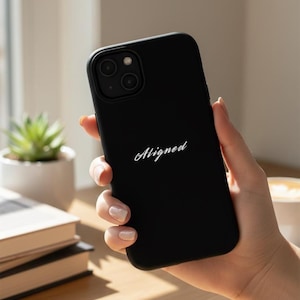 Funda negra mate para iPhone con cita cursiva blanca "Alineada", compatible con MagSafe