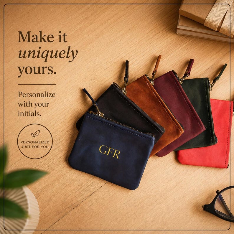 Pu&ograve; includere: Una collezione di portamonete in pelle personalizzate in vari colori, tra cui blu navy, nero, marrone, bordeaux, verde scuro e rosso. Ogni portamonete presenta una chiusura con cerniera e iniziali dorate. Il testo "Make it uniquely yours" &egrave; visibile.