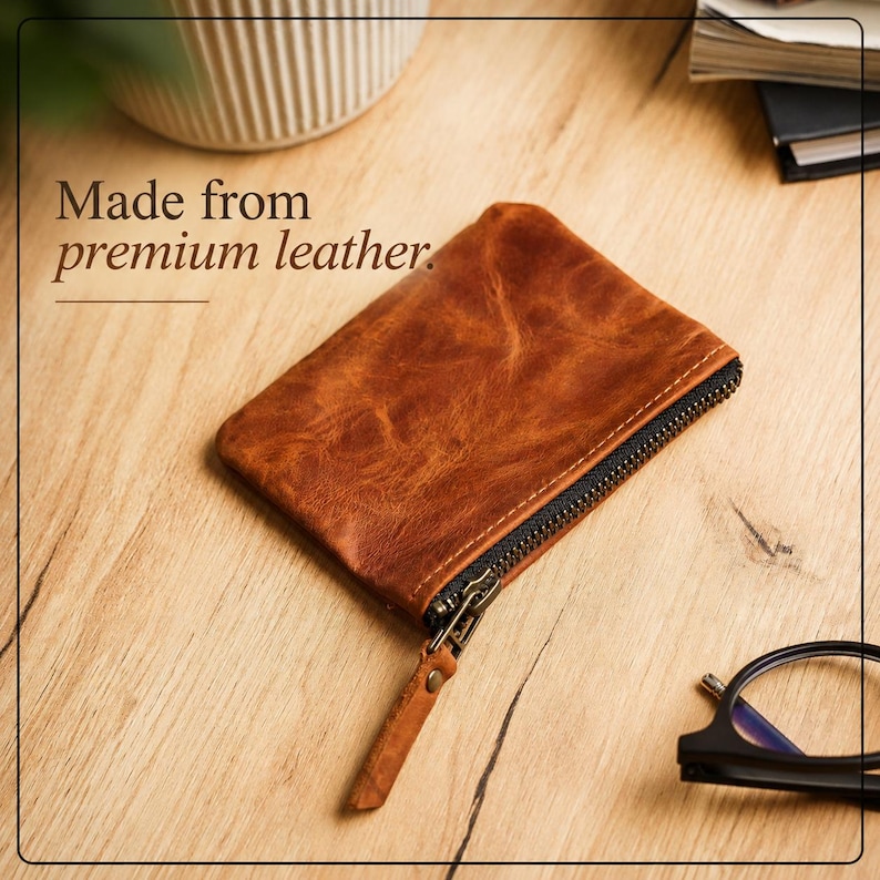 Pu&ograve; includere: Un portamonete in pelle marrone con cerniera nera e linguetta in pelle. Il portamonete &egrave; rettangolare e ha una superficie strutturata. Il testo "Made from premium leather" &egrave; visibile.