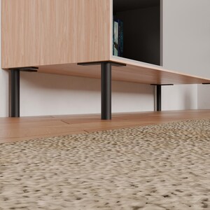 Könnte beinhalten: Ein helles Holzschrank mit schwarzen Metallbeinen. Der Schrank hat eine rechteckige Form mit einem Regal und einem dunklen Innenraum. Die Beine sind zylindrisch und bieten Halt. Der Schrank steht auf einem Holzboden.
