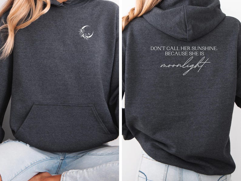 K&ouml;nnte beinhalten: Dunkelgrauer Kapuzenpullover mit Fronttasche und Kapuze. Die Vorderseite zeigt einen wei&szlig;en Halbmond und ein Blumendesign. Auf der R&uuml;ckseite steht der Text "DON'T CALL HER SUNSHINE... BECAUSE SHE IS moonlight" in wei&szlig;er Schrift.