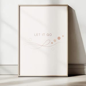 Op de afbeelding: Een ingelijste kunstdruk met de woorden "LET IT GO" in een zachtbruin lettertype. Het kunstwerk heeft een minimalistisch ontwerp met vloeiende lijnen en cirkels in bruin- en roze tinten, tegen een crèmekleurige achtergrond.
