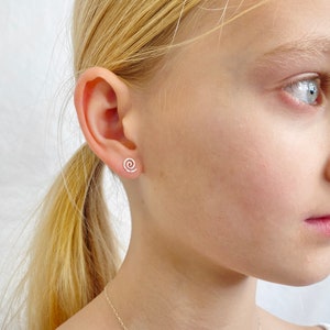 Spiral sterling silver hammered stud earrings on a child model with blond hair