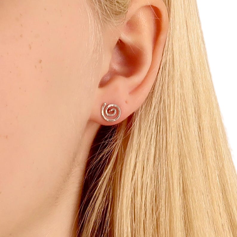 Spiral sterling silver hammered stud earrings on a model with blond hair
