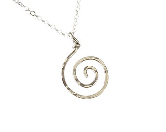 Puede incluir: Un collar de plata con un colgante de espiral martillado.