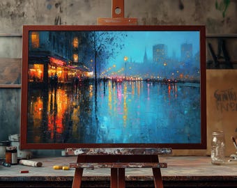 May include: A framed painting on an easel depicts a rainy cityscape at night. The artwork features a street scene with reflections of lights in the wet pavement, rendered in blues, oranges, and yellows. The painting is displayed in a studio setting.