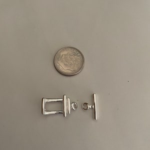 May include: Silver toggle clasp for jewelry making. The clasp is made of two pieces, a rectangular piece with a loop and a bar with a loop. The clasp is about the size of a US dime.