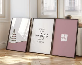 May include: Three framed prints with a pink background. The left print features a stylized green Christmas tree. The middle print has the text "It's the most wonderful time of the year". The right print has a white gift box with a pink ribbon.