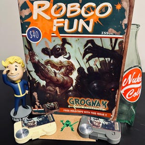 May include: A selection of Fallout-themed items: a "Robco Fun" comic book, a Vault-Tec figurine, two Grognak holotape players, and a Nuka-Cola bottle. The comic book displays the text "Grognak" and a battle scene.