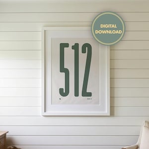 May include: A framed print featuring the number "512" in a bold, dark green font. The artwork is displayed on a white wall with horizontal paneling. A "DIGITAL DOWNLOAD" sticker is visible. The room includes a desk and chair.