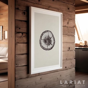 May include: A framed black and white print of a tree trunk cross-section with visible rings. The print is hanging on a wooden wall with a white frame. The text "LARIAT SUPPLY CO." is visible in the bottom right corner of the image.