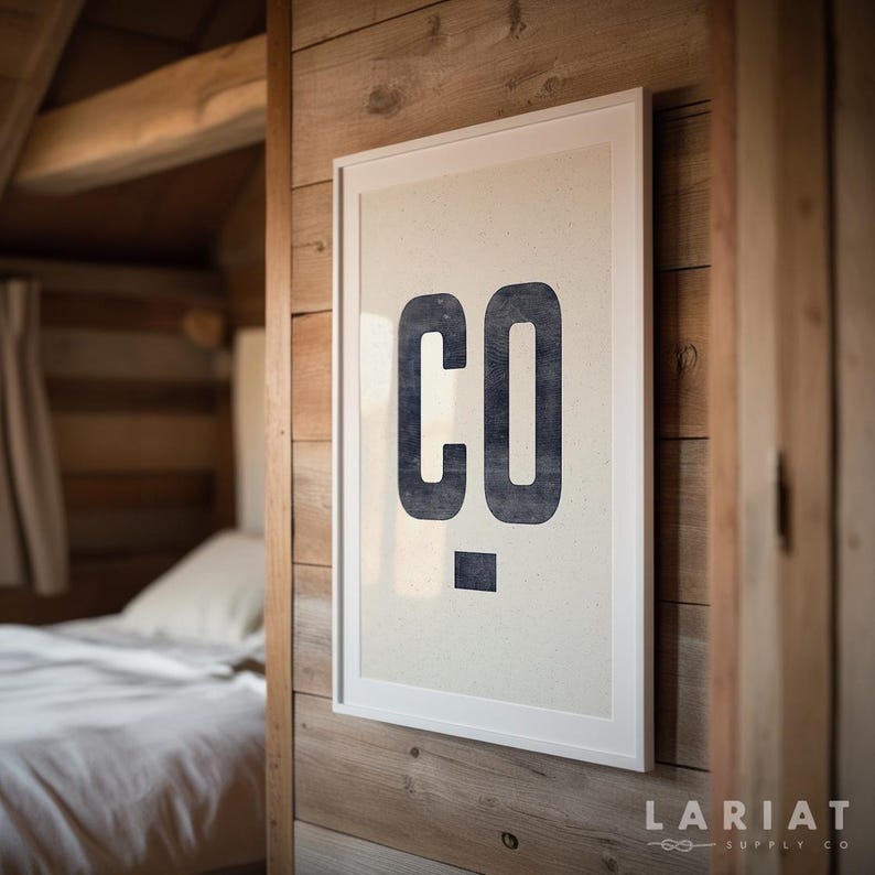 Puede incluir: Un estampado enmarcado con las letras "CO" en azul oscuro y negrita. La impresi&oacute;n est&aacute; montada sobre un fondo beige claro y enmarcada en blanco. La impresi&oacute;n est&aacute; colgada en una pared de madera.
