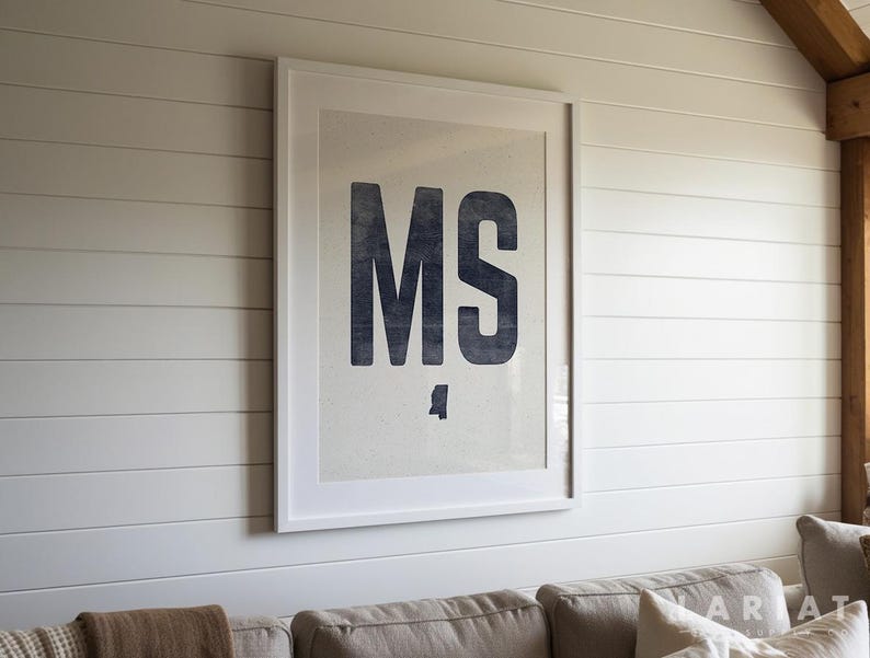 Op de afbeelding: Een ingelijste print met de letters "MS" in een donkerblauwe, vette letter. De print staat tegen een lichte achtergrond en is omlijst met een witte rand. Het kunstwerk is gemonteerd op een witte lambrisering.
